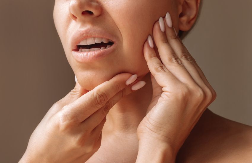 Persona tocándose la mandíbula con gesto de molestia, ilustrando cambios en la mordida o dolor mandibular.